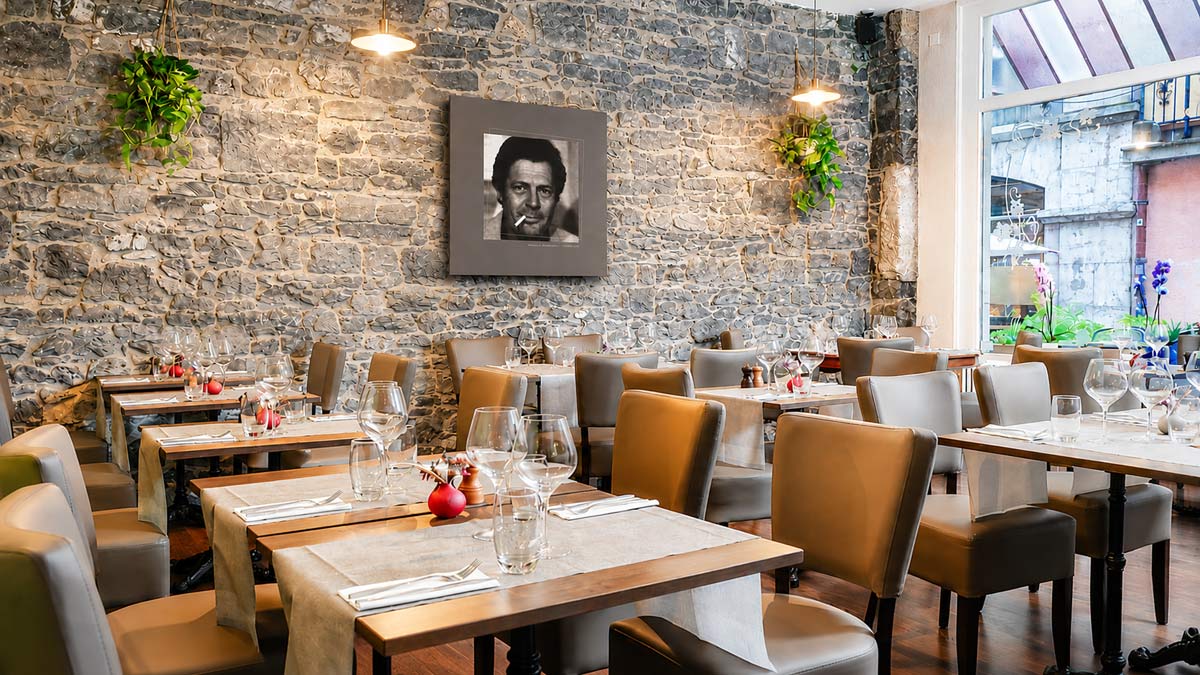 Salle du restaurant italien L’Aurora à Genève avec mur en pierre et ambiance chaleureuse